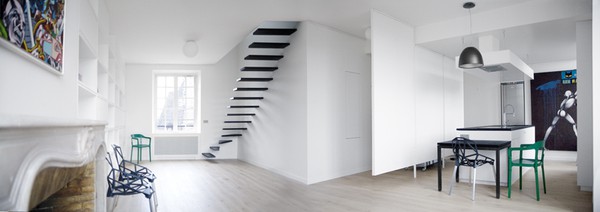Просторная белая комната с контрастными черными ступенями лестницы.